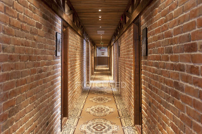 Un hotel con camere in stile retrò vecchio stile, e oggetti rustici, corridoio con tappeto fantasia, porte della camera. — Foto stock