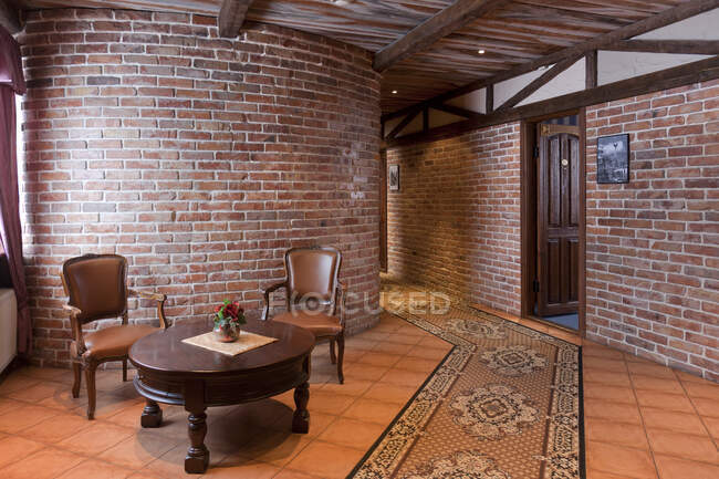 Un hotel con habitaciones antiguas de estilo retro, y objetos rústicos, pared de piedra vista y mesa y sillas - foto de stock