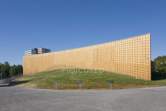 Edifícios universitários modernos, vigas de madeira projetadas a partir de uma parede de revestimento de madeira curva, em uma superfície de solo curvo — Fotografia de Stock