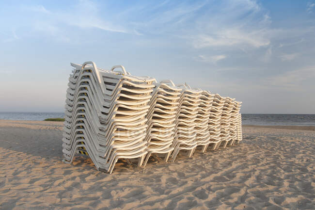 Sillas de salón apiladas en una playa - foto de stock