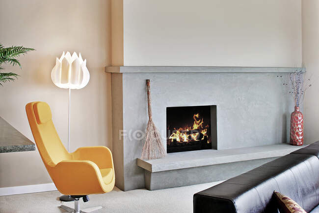 Вітальня в сучасному будинку, з каміном і мантією і вогнищем, і сучасним жовтим стільцем . — стокове фото