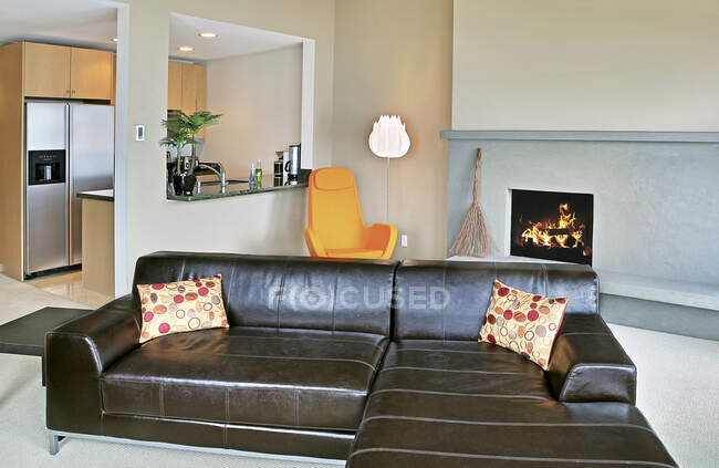 Salon et cuisine décloisonnés dans une maison moderne, une cheminée éclairée et un canapé sectionnel. — Photo de stock