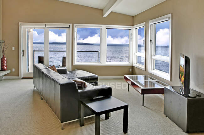 Sala de estar em uma casa à beira-mar, com uma grande janela e vista para o mar. — Fotografia de Stock
