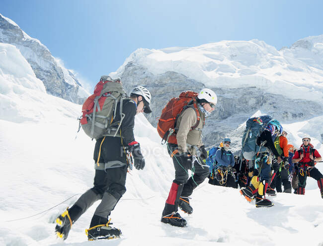 Gruppo di escursionisti zaino in spalla sul sentiero di montagna innevato — Foto stock