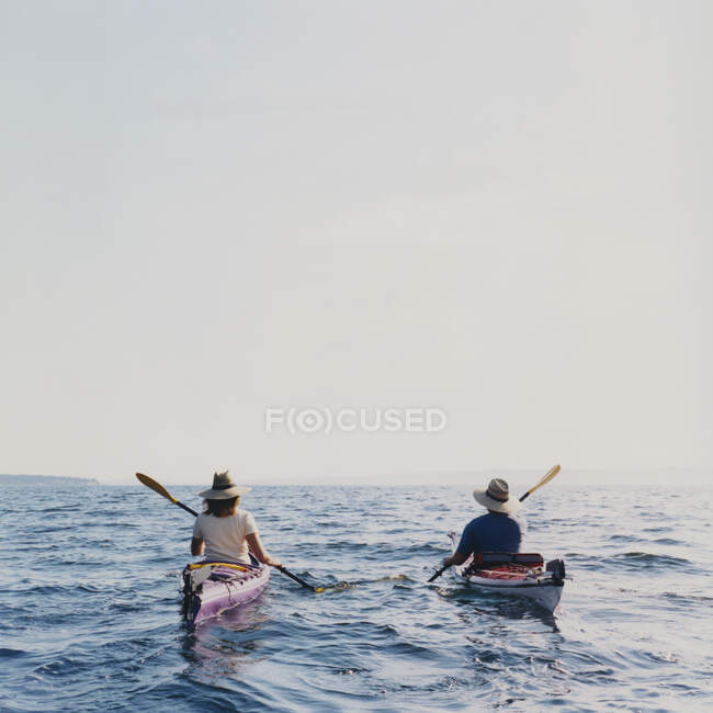 Middle aged man and woman sea kayaking at dusk — Stock Photo