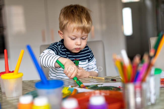 Dreijähriger Junge malt zu Hause mit Farbtöpfen und Pinseln. — Stockfoto