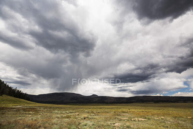 A stormy sky with heavy grey clouds, mountains in the distance. — Stock Photo