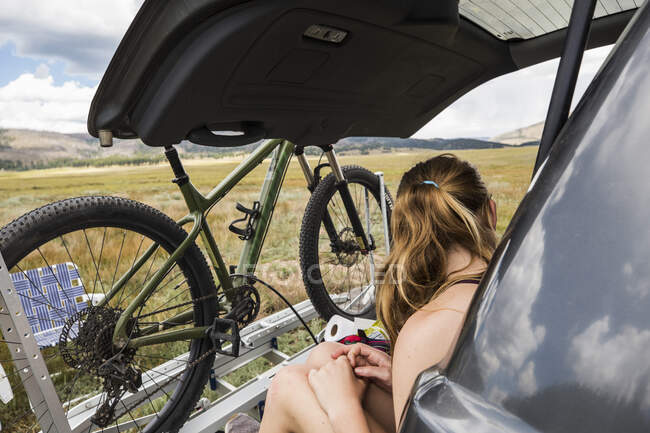 Ragazza adolescente seduta sul portellone di un SUV guardando la vista — Foto stock