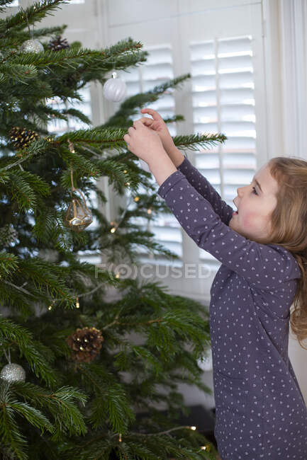 Jeune fille décorant arbre de Noël avec des boules. — Photo de stock