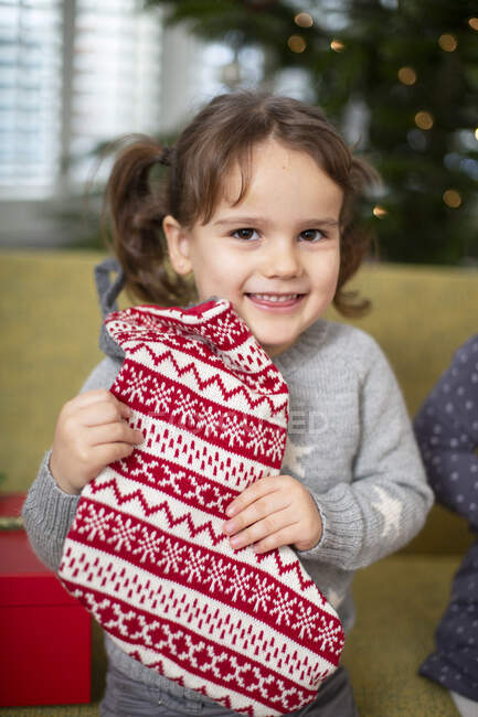Молодая девушка держит красный и белый рождественский чулок, улыбаясь в камеру. — стоковое фото