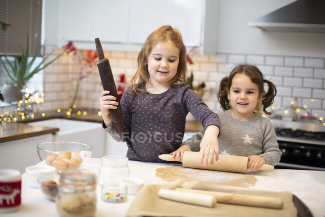 Two girls standing in kitchen, baking Christmas cookies. — Stock Photo
