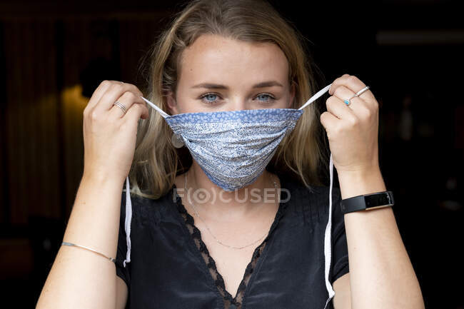 Retrato de jovem loira colocando em máscara facial azul. — Fotografia de Stock