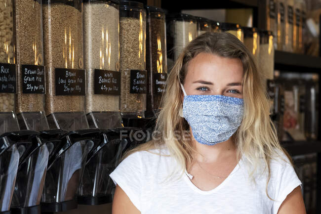 Mujer con mascarilla de compras en tienda local libre de residuos - foto de stock