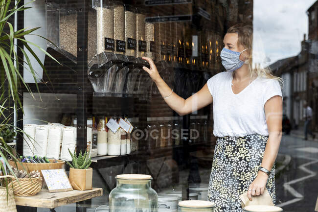 Mulher vestindo máscara facial compras na loja local sem resíduos — Fotografia de Stock