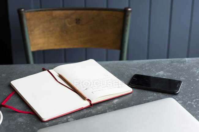 Großaufnahme von Notizbuch, Handy und Laptop auf einem Cafétisch. — Stockfoto