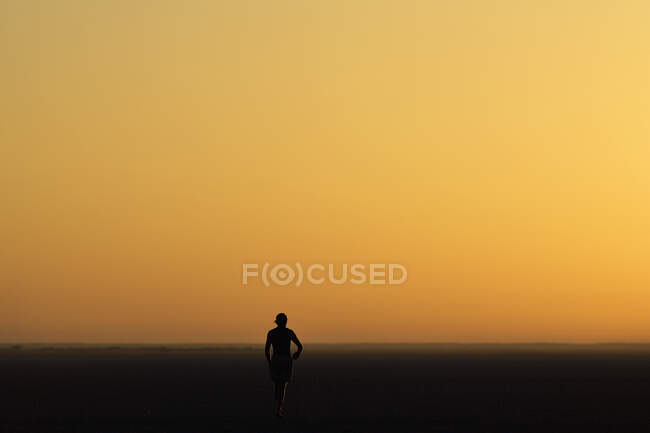Person walking across the Makadikadi Salt Pans in Botswana, at sunset. — Stock Photo