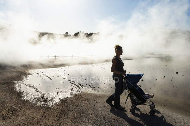 Женщина и ребенок в коляске, поднимают пар из термальных бассейнов — стоковое фото
