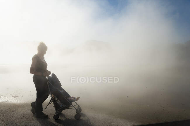 Mujer y niño en buggy en el aumento de vapor de las piscinas termales - foto de stock