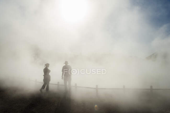 Два человека в поднимающемся тумане на термальном бассейне — стоковое фото