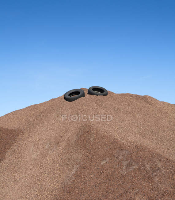 Cumulo di ghiaia con pneumatici di gomma, cielo blu — Foto stock