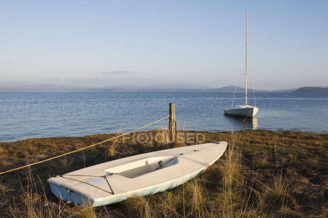 Petits bateaux sur la côte, échoués sur le sable et amarrés dans l'eau — Photo de stock