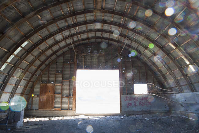 Interior of a deserted building, big open door and arched roof — Stock Photo