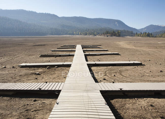 Planken als Stege angelegt, Stege auf flachem trockenen Wüstenboden, offener Raum. — Stockfoto