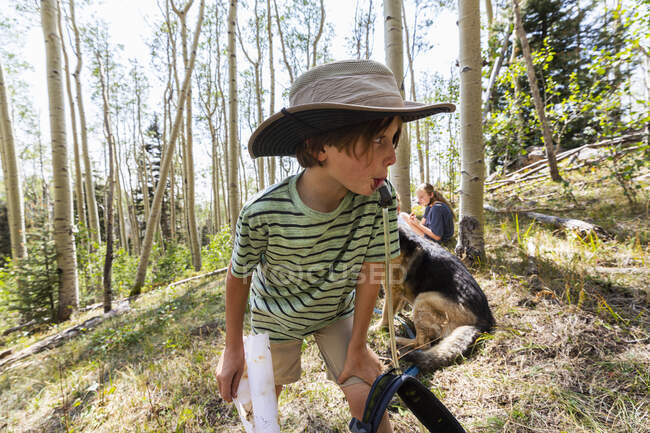 Menino de 7 anos de idade bebendo água do pacote de hidratação na floresta de árvores de Aspen — Fotografia de Stock