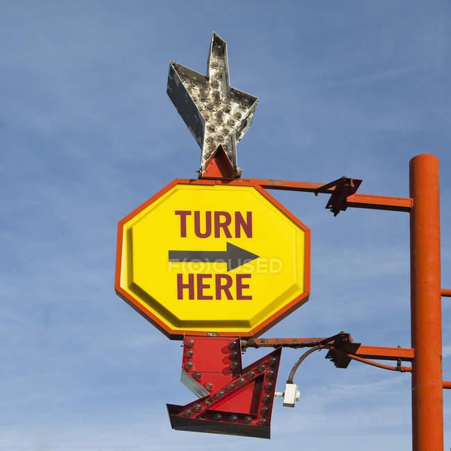 Turn Here, yellow traffic sign with arrow, on a gantry with a silver star shape — Fotografia de Stock