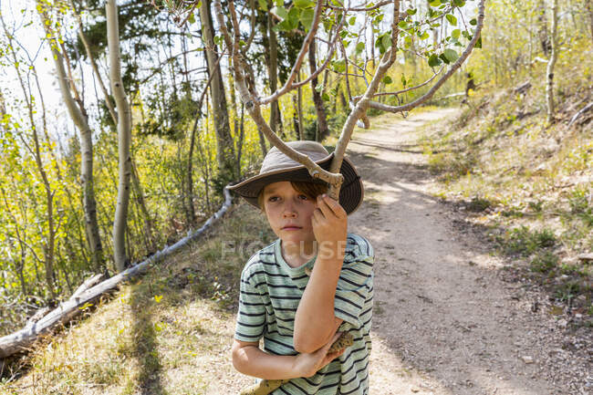 Siebenjähriger Junge hält abgebrochenen Ast im Wald von Aspen — Stockfoto