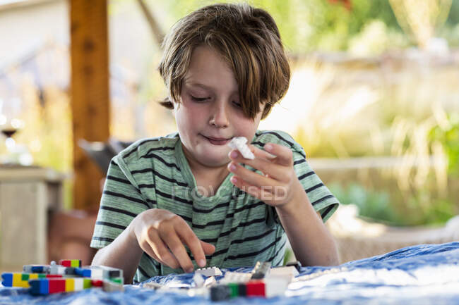 7-летний мальчик играет со строительными блоками на террасе — стоковое фото