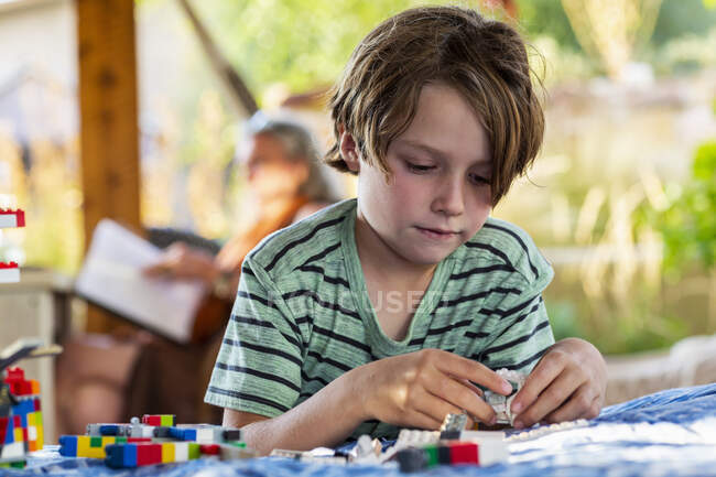 Menino de sete anos brincando com blocos de construção em um terraço — Fotografia de Stock