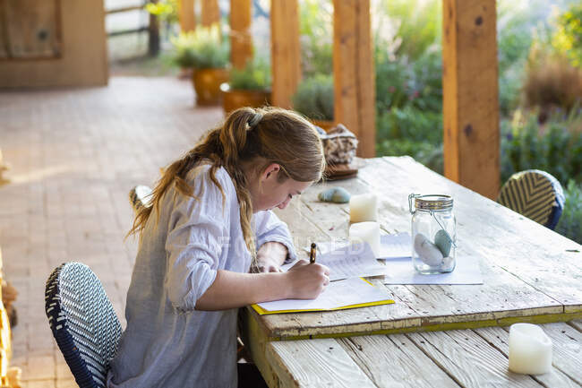 Teenage girl writing outside on terrace at sunset. — Stock Photo