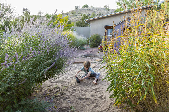 Siebenjähriger Junge spielt mit seinem Spielzeugschiff im Sandgarten. — Stockfoto