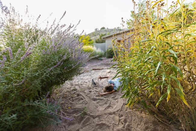Seven year old boy playing in sandy garden with his toy ship. — Stock Photo
