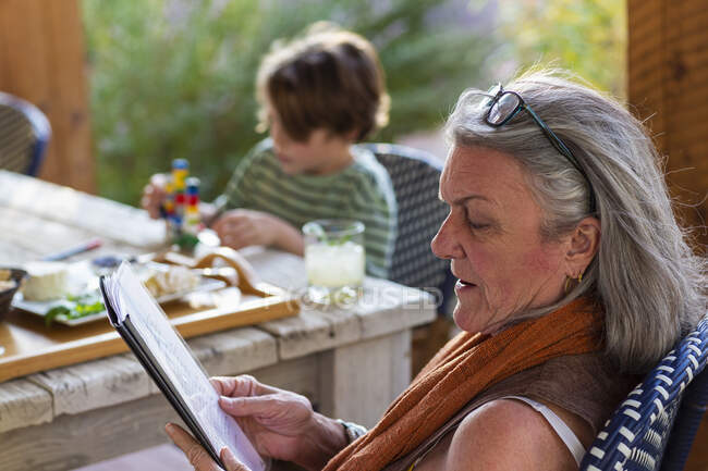 Mujer leyendo archivo afuera en la terraza al atardecer. - foto de stock