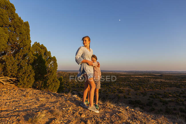 Adolescente embrassant son frère cadet dans le bassin de Galisteo, Santa Fe, NM. — Photo de stock