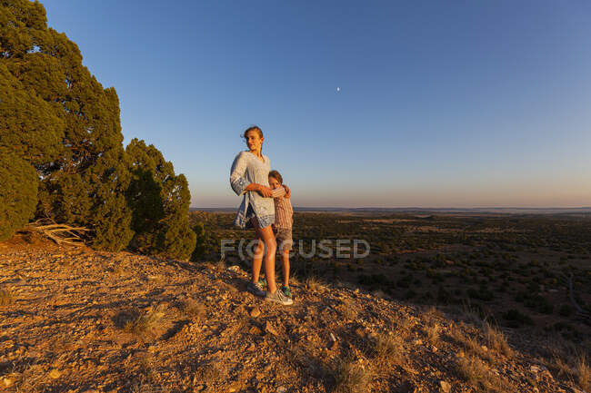 Adolescente abrazando a su hermano menor en la Cuenca del Galisteo, Santa Fe, NM. - foto de stock