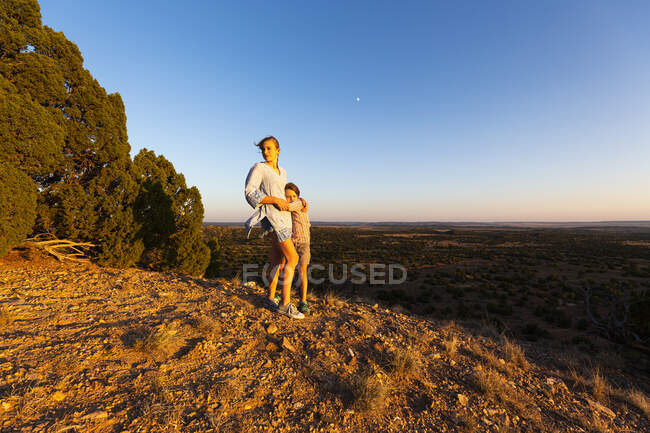 Adolescente abrazando a su hermano menor en la Cuenca del Galisteo, Santa Fe, NM. - foto de stock