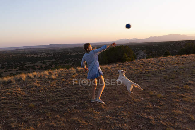 Adolescente chica lanzando fútbol al atardecer. - foto de stock