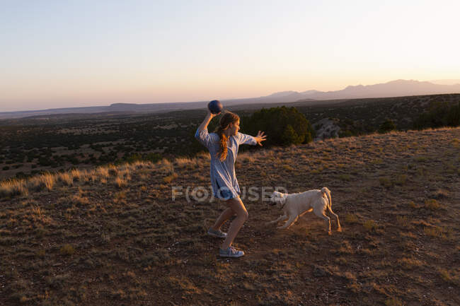 Дівчина-підліток кидає футбол на заході сонця . — стокове фото