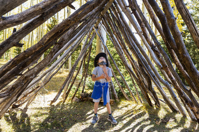 Young boy looking up, standing in a tunnel made of tree logs. — Stock Photo