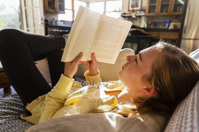 Adolescent fille lecture livre à la maison tôt le matin lumière — Photo de stock