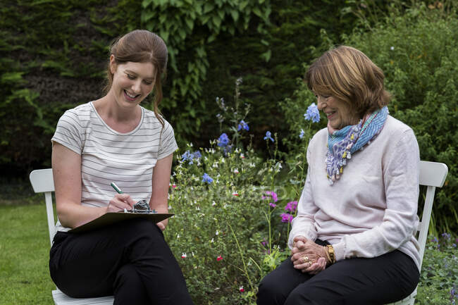 Mujer y terapeuta en una sesión de terapia alternativa en un jardín. - foto de stock