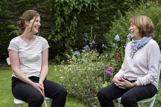 Mulher e terapeuta sentada em uma sessão de terapia alternativa em um jardim. — Fotografia de Stock