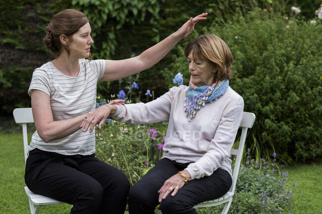 Reiki therapist with a client in a therapy session touching meridian points on the body. — Stock Photo