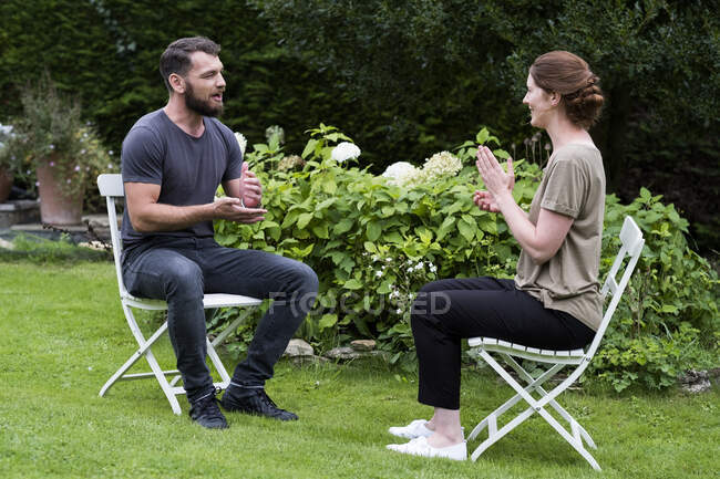 Hombre y terapeuta sentados en un jardín, hablando. - foto de stock