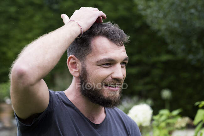 Mann sitzt im Garten und klopft sich auf den Kopf, EFT-Therapie. — Stockfoto