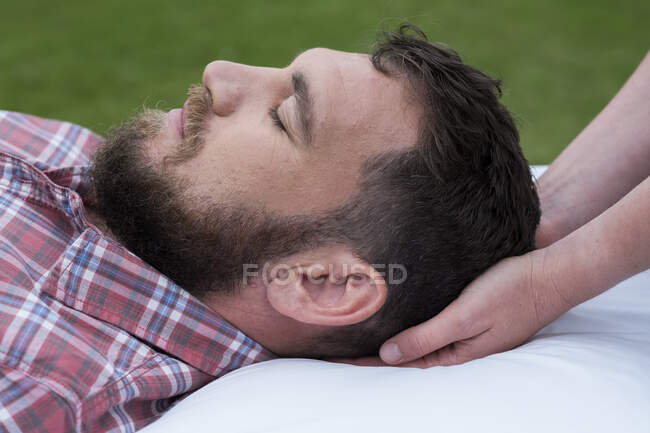 Homem deitado em um sofá, terapeuta embalando a cabeça. — Fotografia de Stock