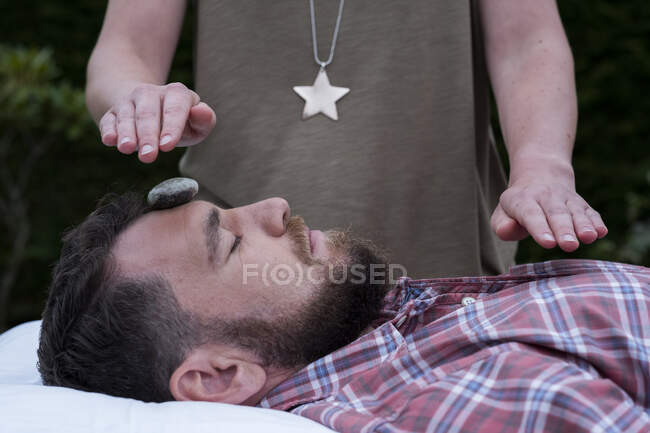 A man on a couch with a stone on his forehead, therapy session. — Stock Photo